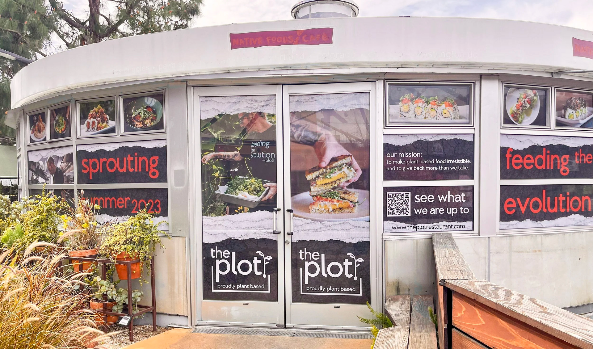 Storefront with glass doors and windows covered in posters and signs, including “plot” and “feeling the evolution.”