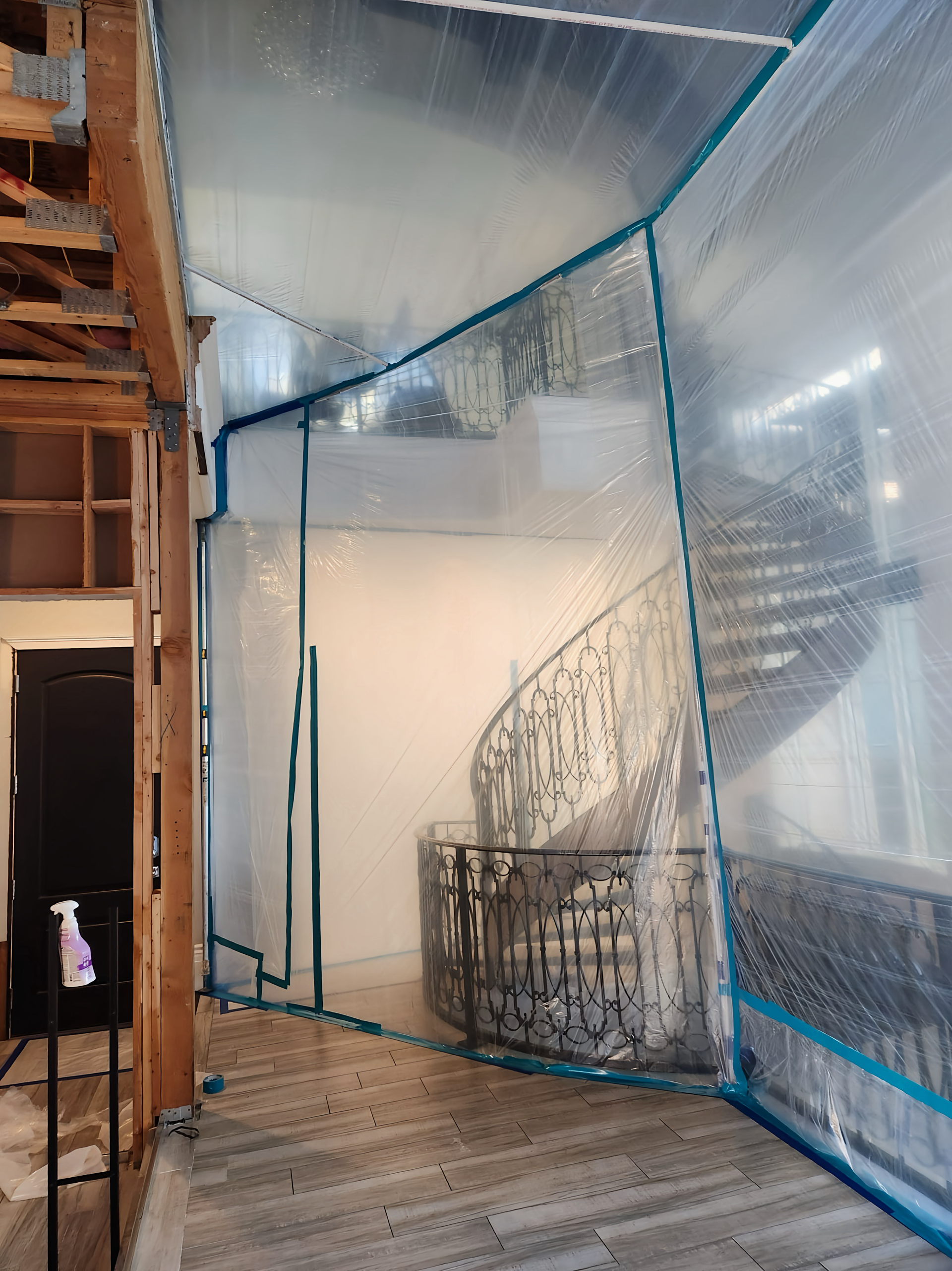 A transparent, plastic-walled structure with a spiral staircase inside. Blue metal framing supports the plastic.