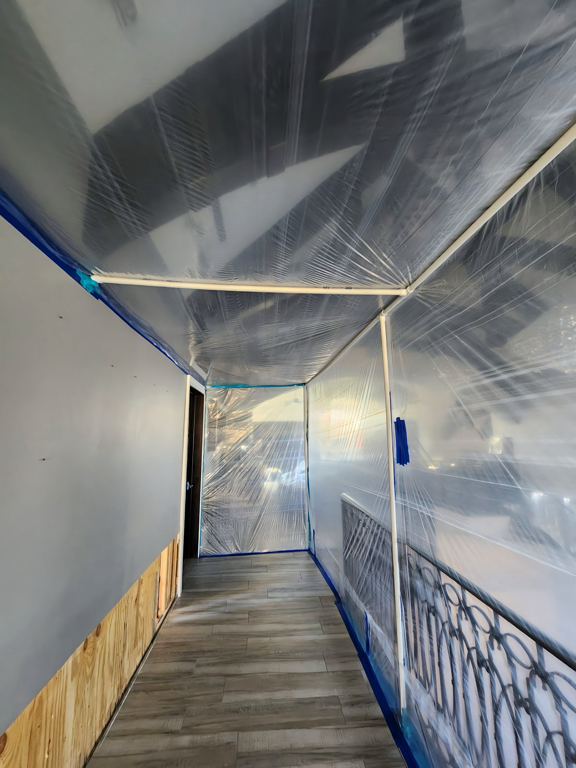 A hallway enclosed in plastic sheeting, likely for dust containment during construction.