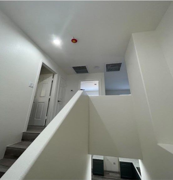 Interior view of a white staircase leading to a hallway with multiple doors and an open space at the top.