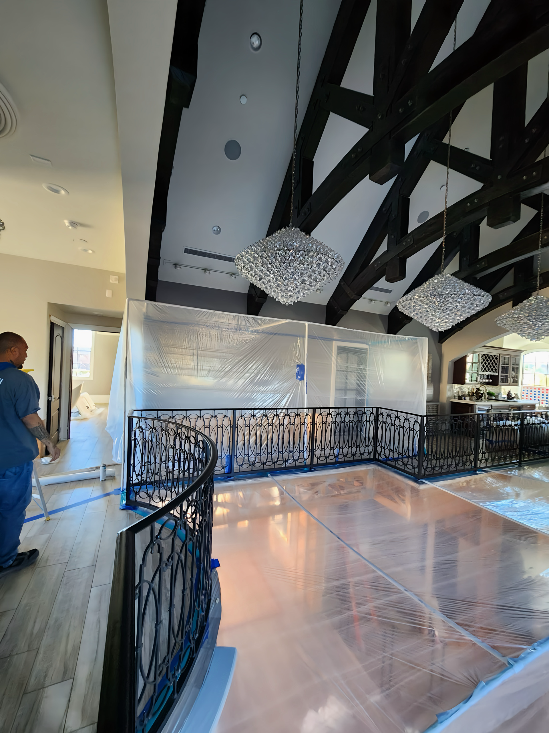 Interior view: a room with high ceilings, exposed wooden beams, and a black wrought iron railing.