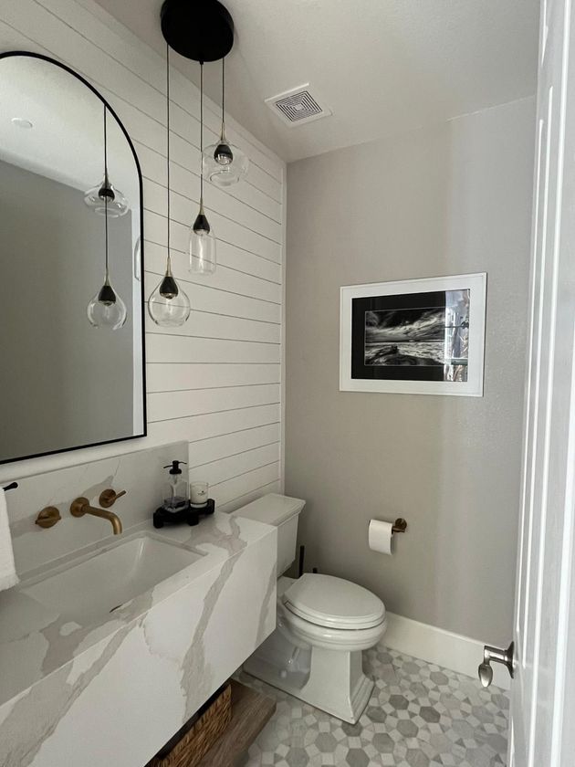 Small modern bathroom with white vanity, black fixtures, toilet, and hanging pendant lights