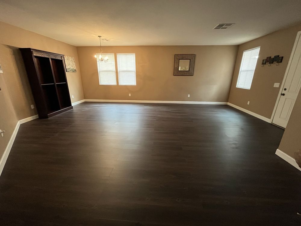 An empty living room with hardwood floors and a bookshelf.