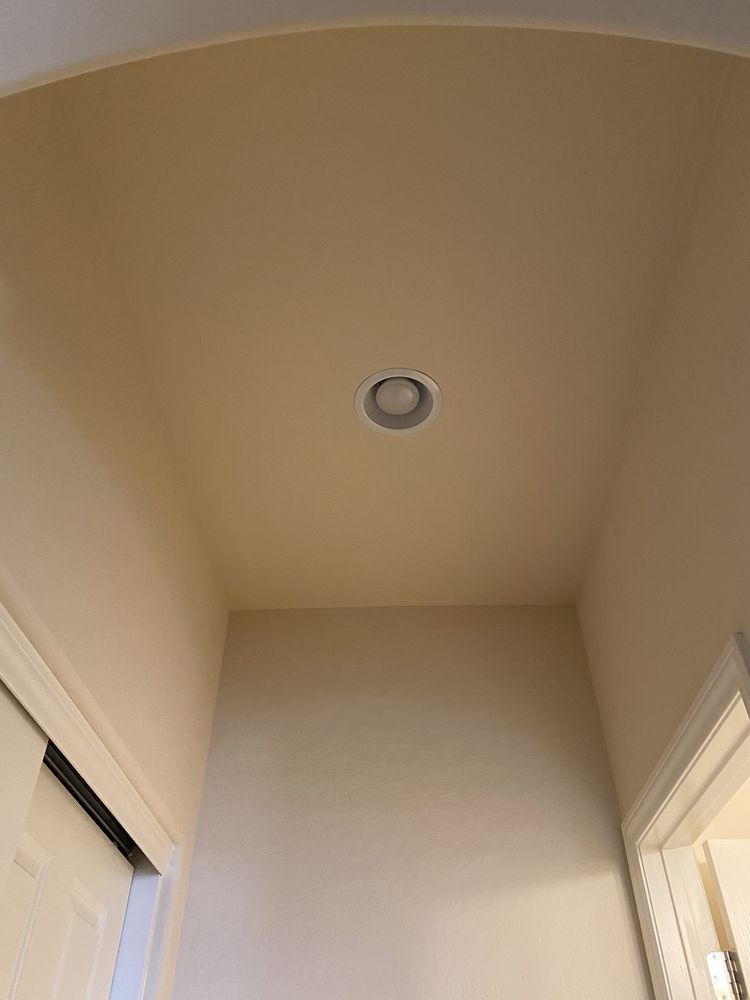 A hallway with a light on the ceiling and a door.