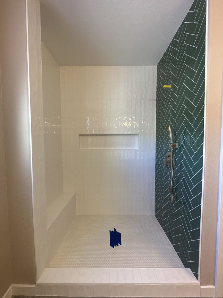 A bathroom with a walk in shower and green tiles.