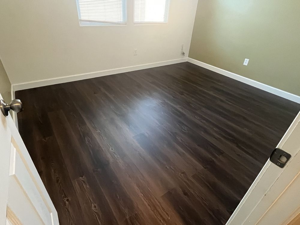 An empty bedroom with hardwood floors and a window.