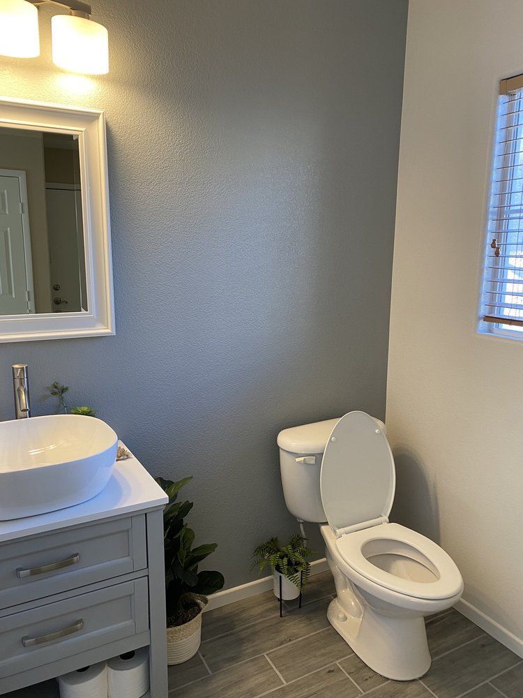 A bathroom with a toilet , sink and mirror.