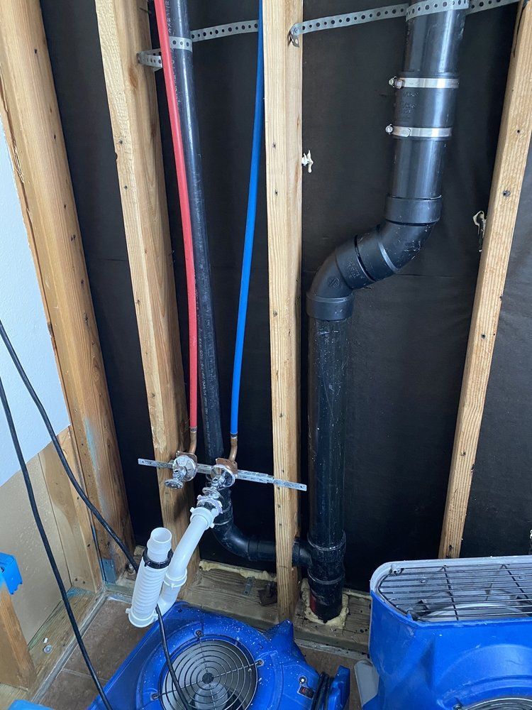 A bathroom with a lot of pipes and a fan.