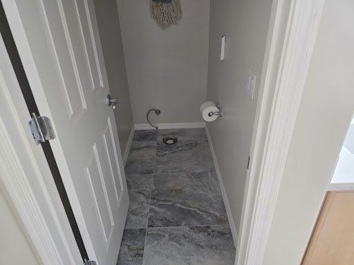 A bathroom with a toilet and a mop on the wall.
