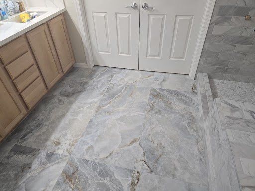 A bathroom with a marble floor and wooden cabinets.