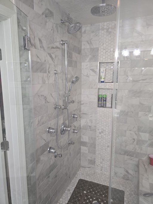 A bathroom with a walk in shower with a glass door and marble tiles.