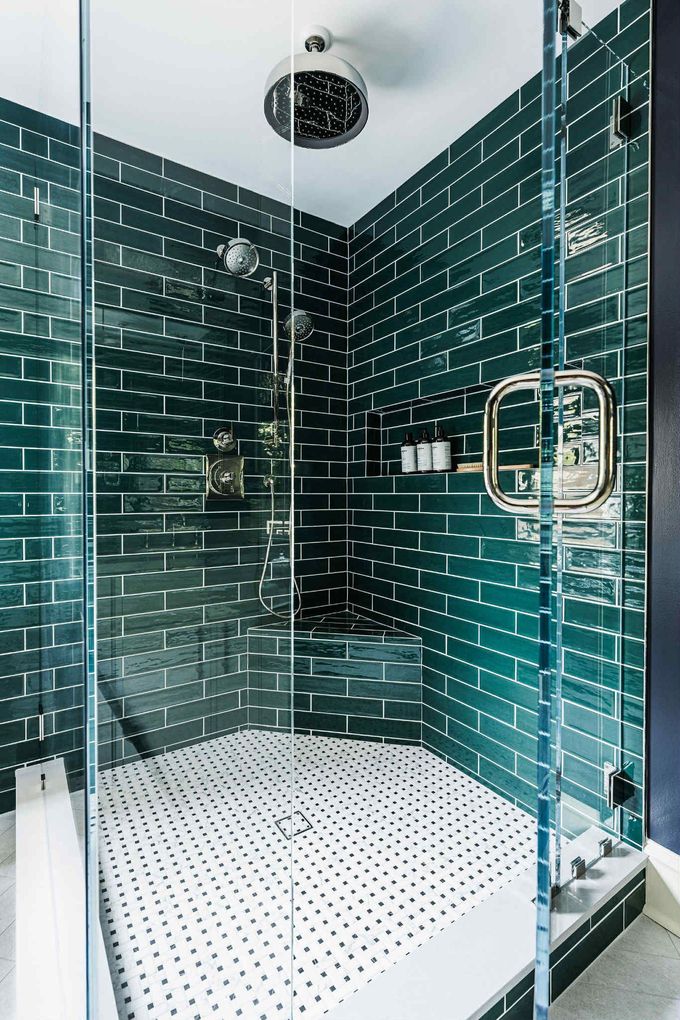 Modern glass shower with dark teal tiled walls and white perforated floor