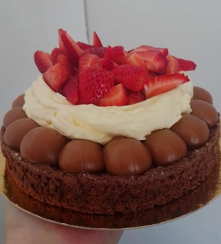 Pastel de chocolate cubierto con caramelos, crema y fresas frescas.