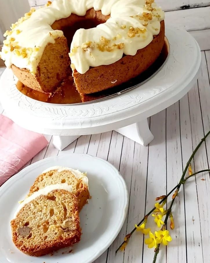 Pastel de zanahoria con glaseado sobre un soporte para pasteles, dos rebanadas en un plato, 