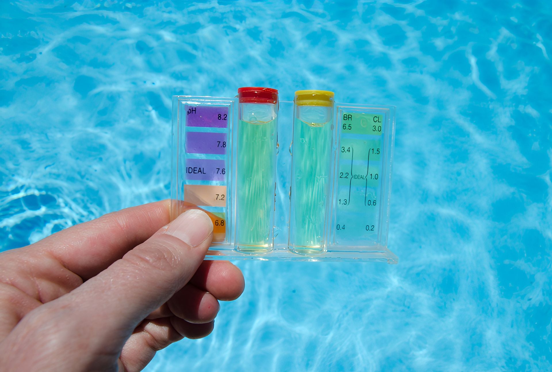 Hand Holding a Pool Water Testing Kit in Front of a Blue Pool — Landsborough Pool Supplies & Service in Sunshine Coast, QLD