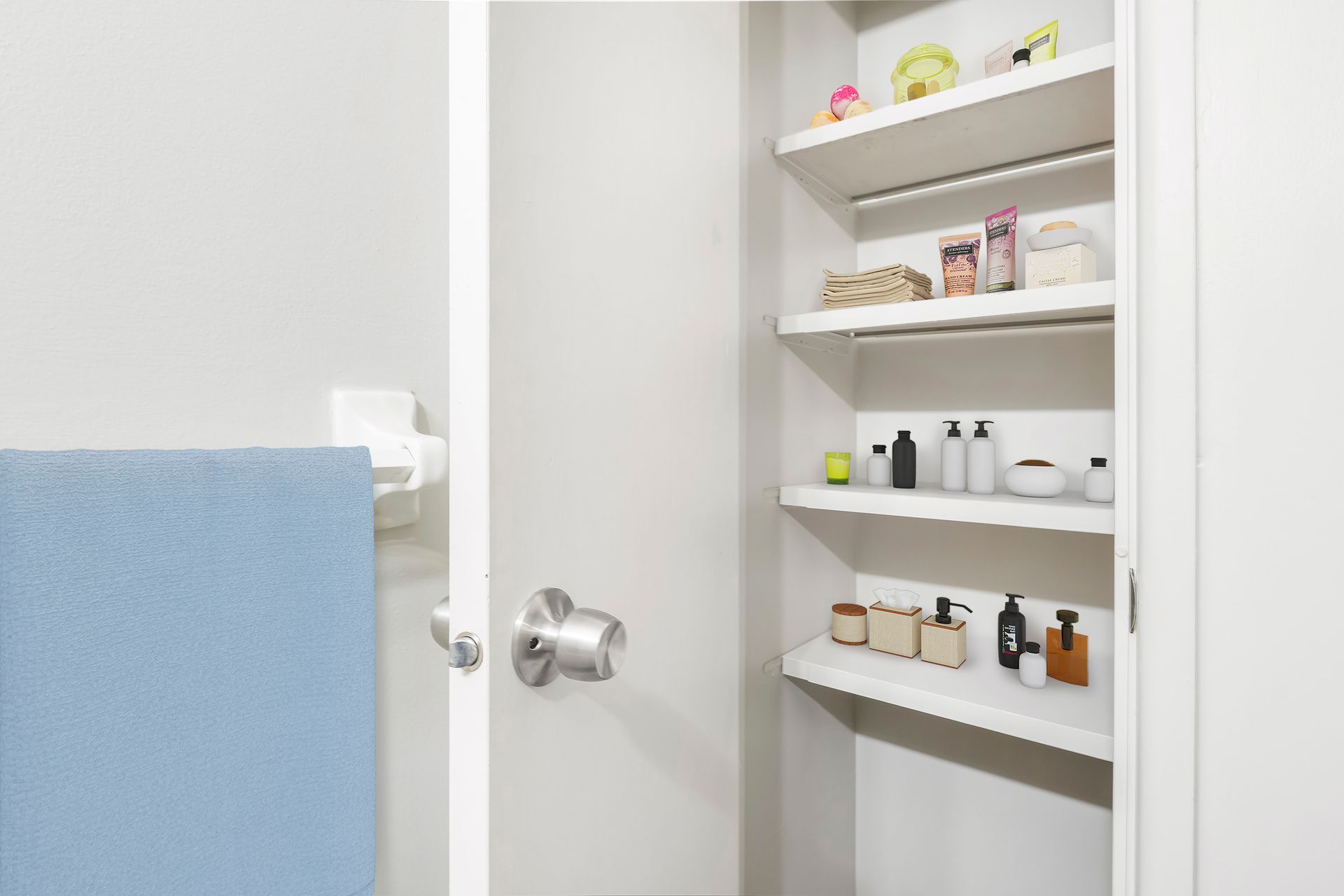 A bathroom with a blue towel and shelves filled with bottles.