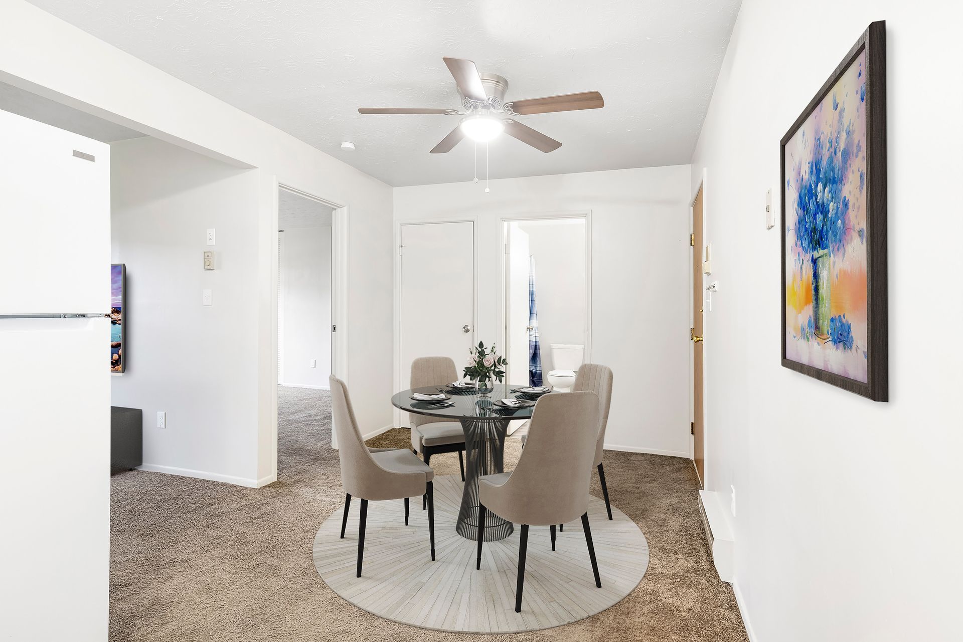 A dining room with a table and chairs and a ceiling fan.