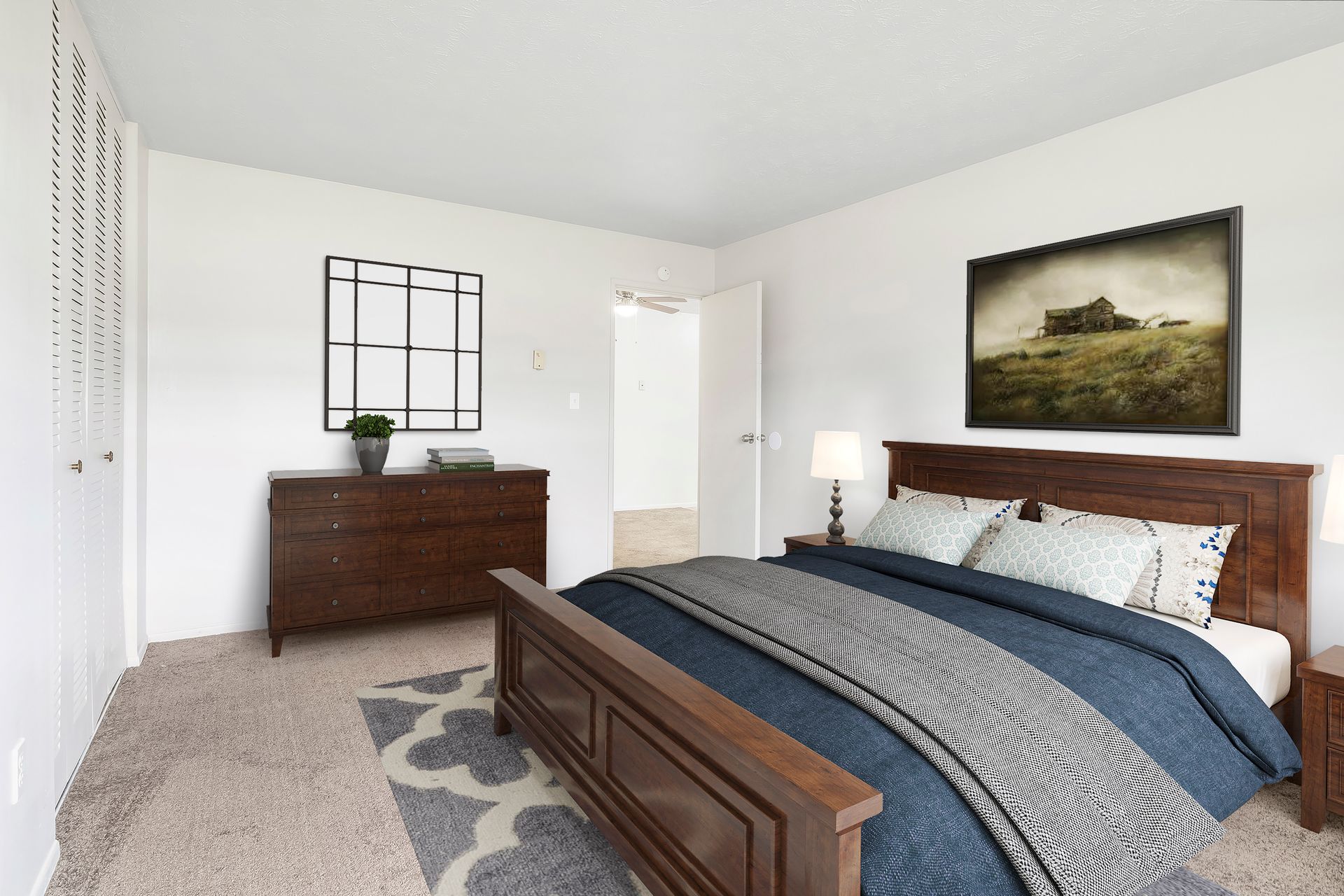 A bedroom with a large bed , dresser , lamp and picture on the wall.