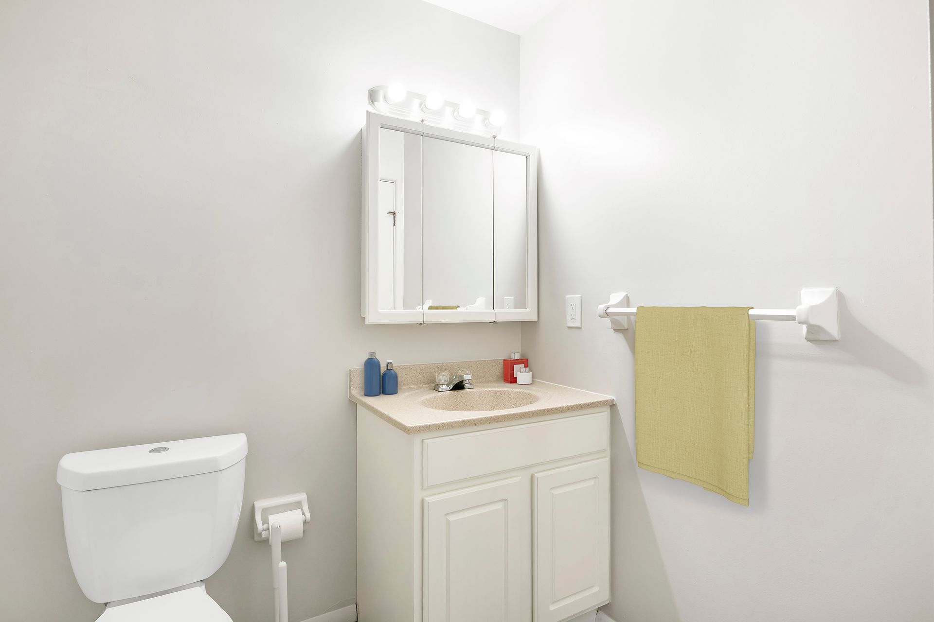 A bathroom with a toilet , sink , mirror and towel rack.