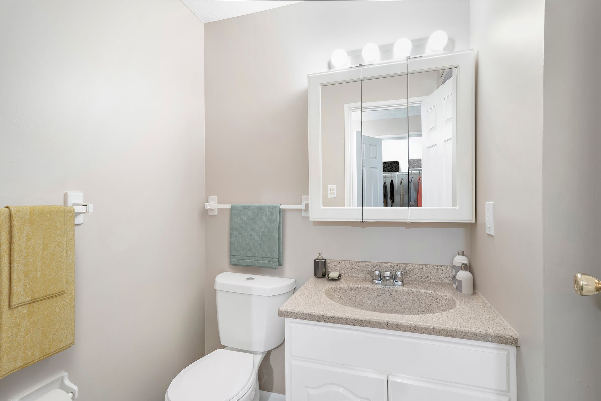 A bathroom with a toilet , sink and mirror.