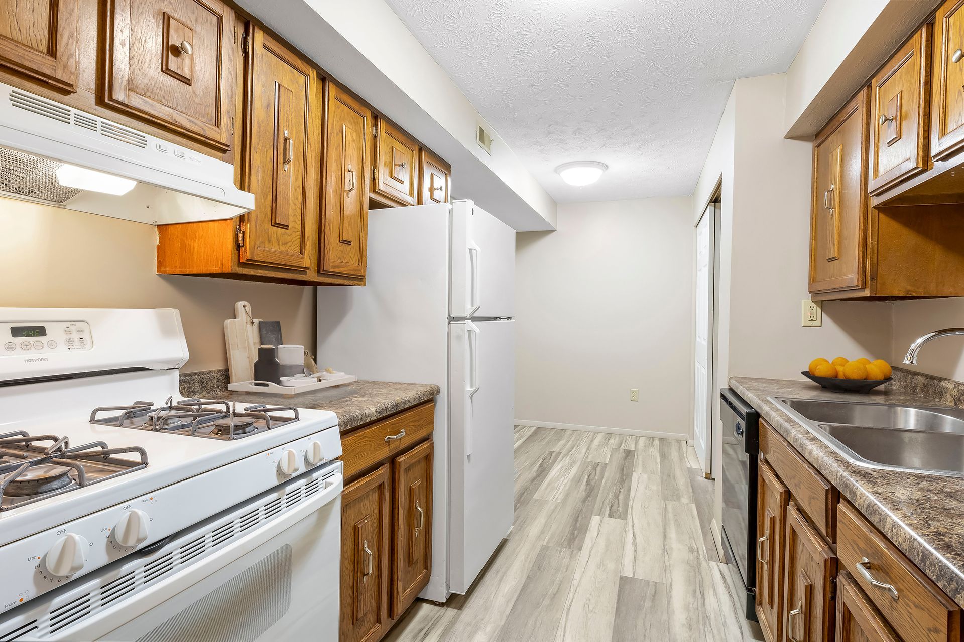 A kitchen with a stove , refrigerator , sink and cabinets.