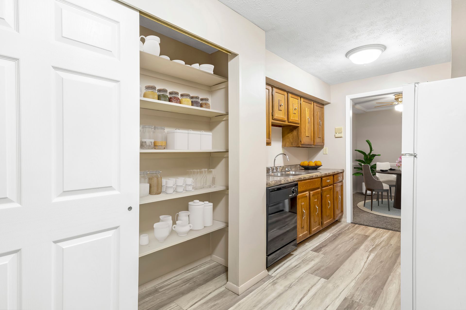 A kitchen with wooden cabinets , a dishwasher , a refrigerator and a pantry.