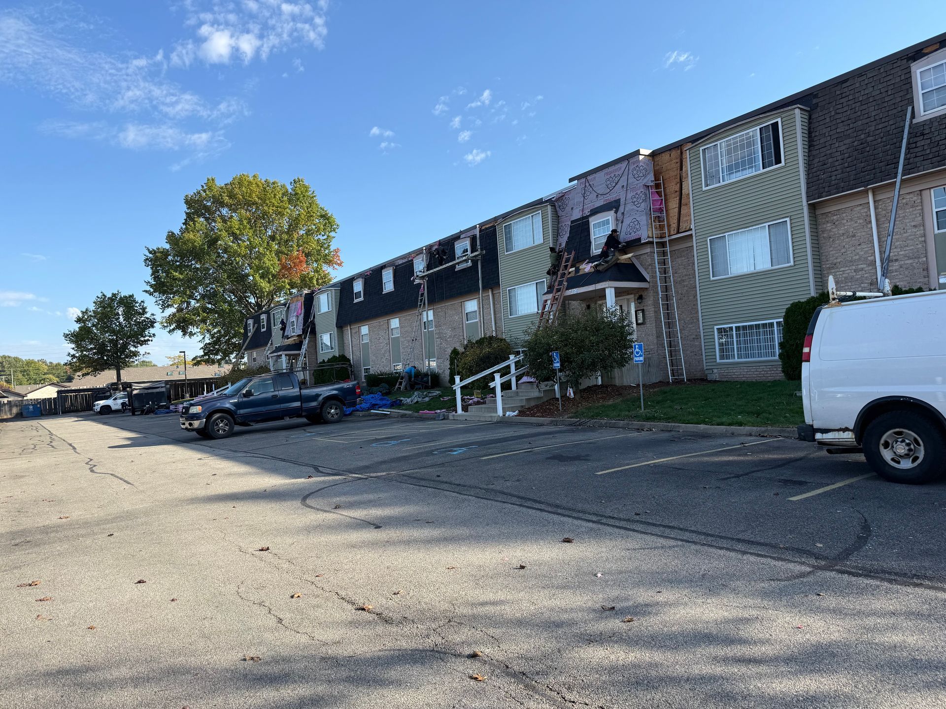 Apartment buildings beside a parking lot with cars under a blue sky