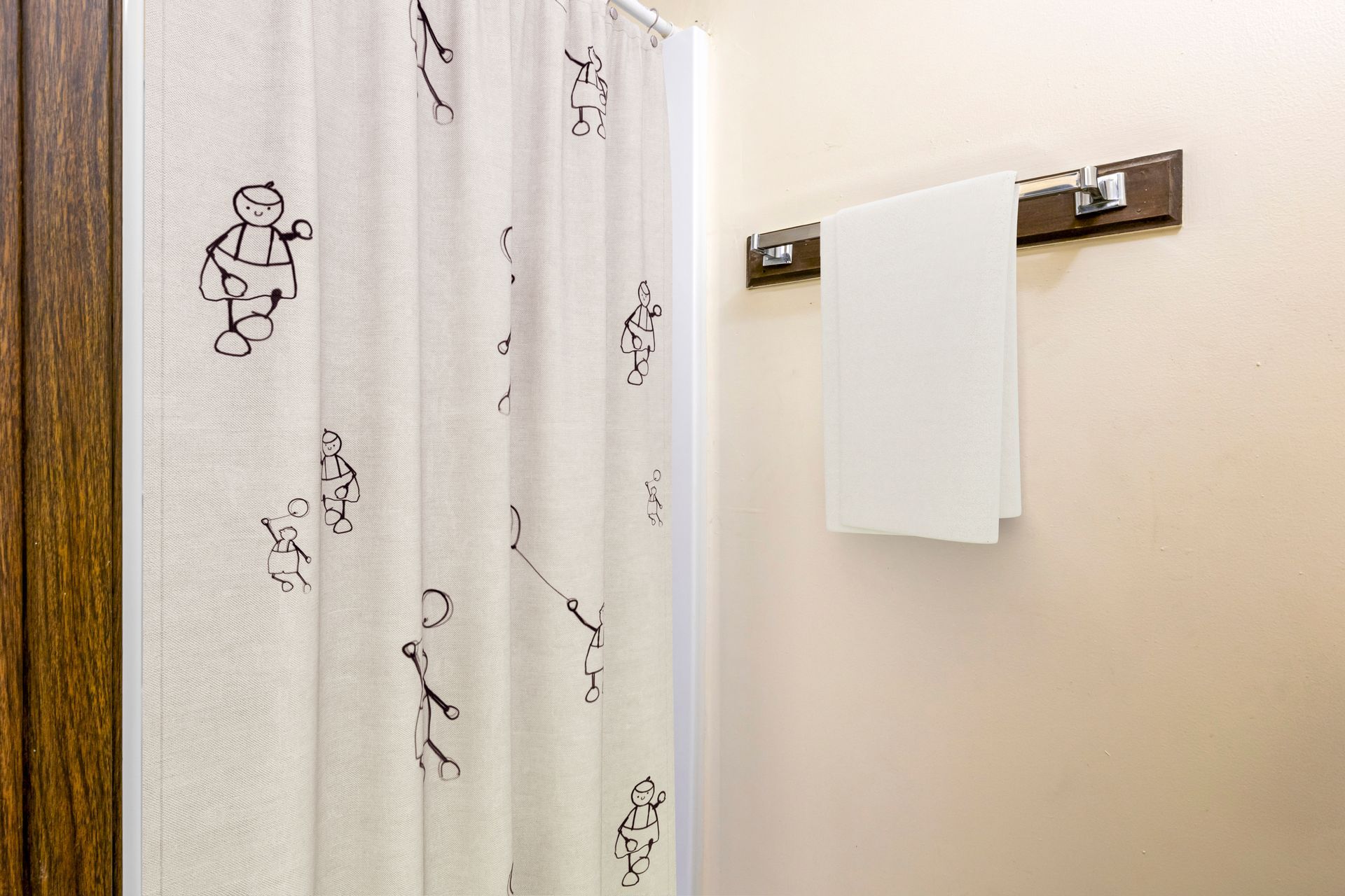 A bathroom with a shower curtain and a towel hanging on the wall