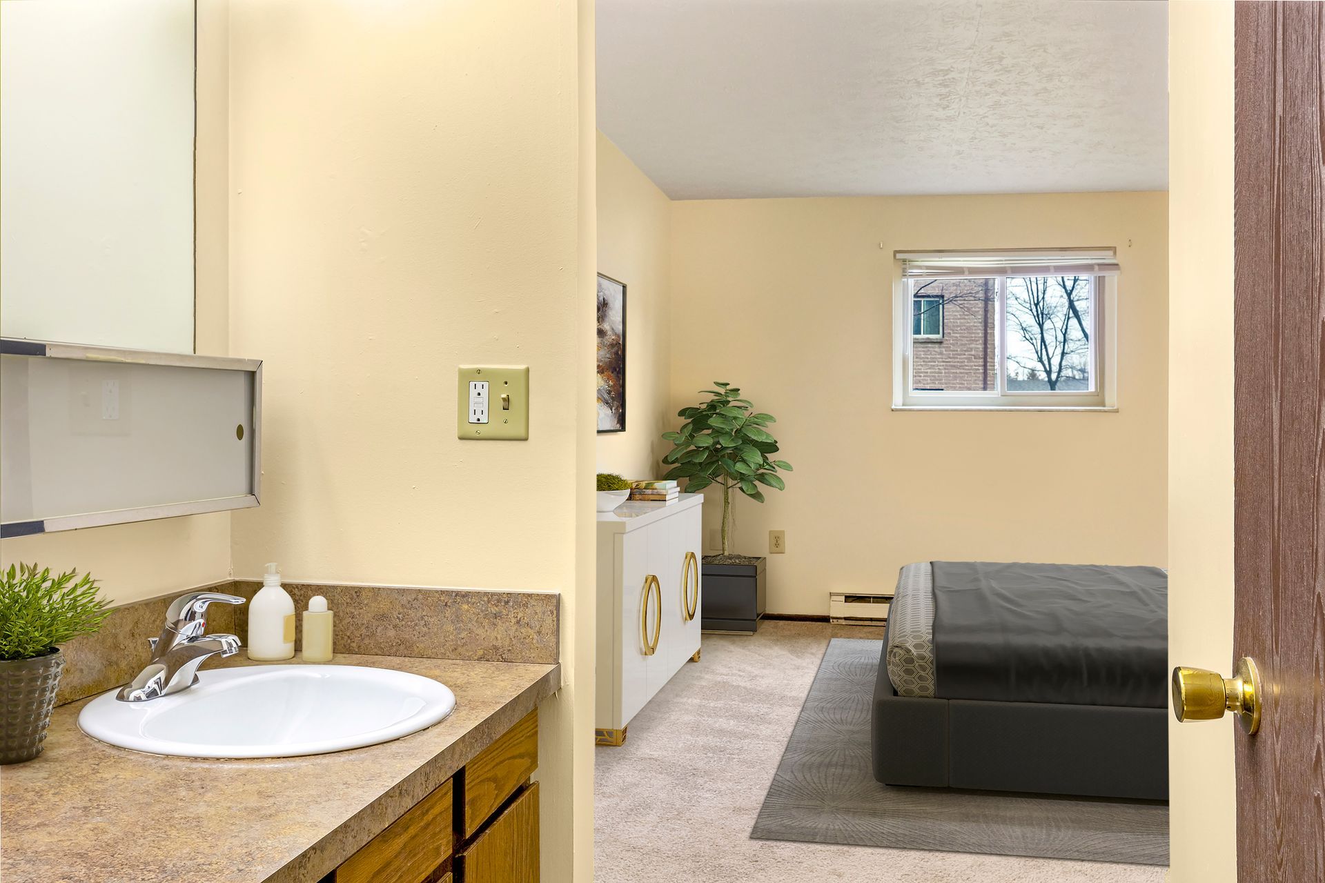 A bathroom with a sink and a mirror next to a bedroom.