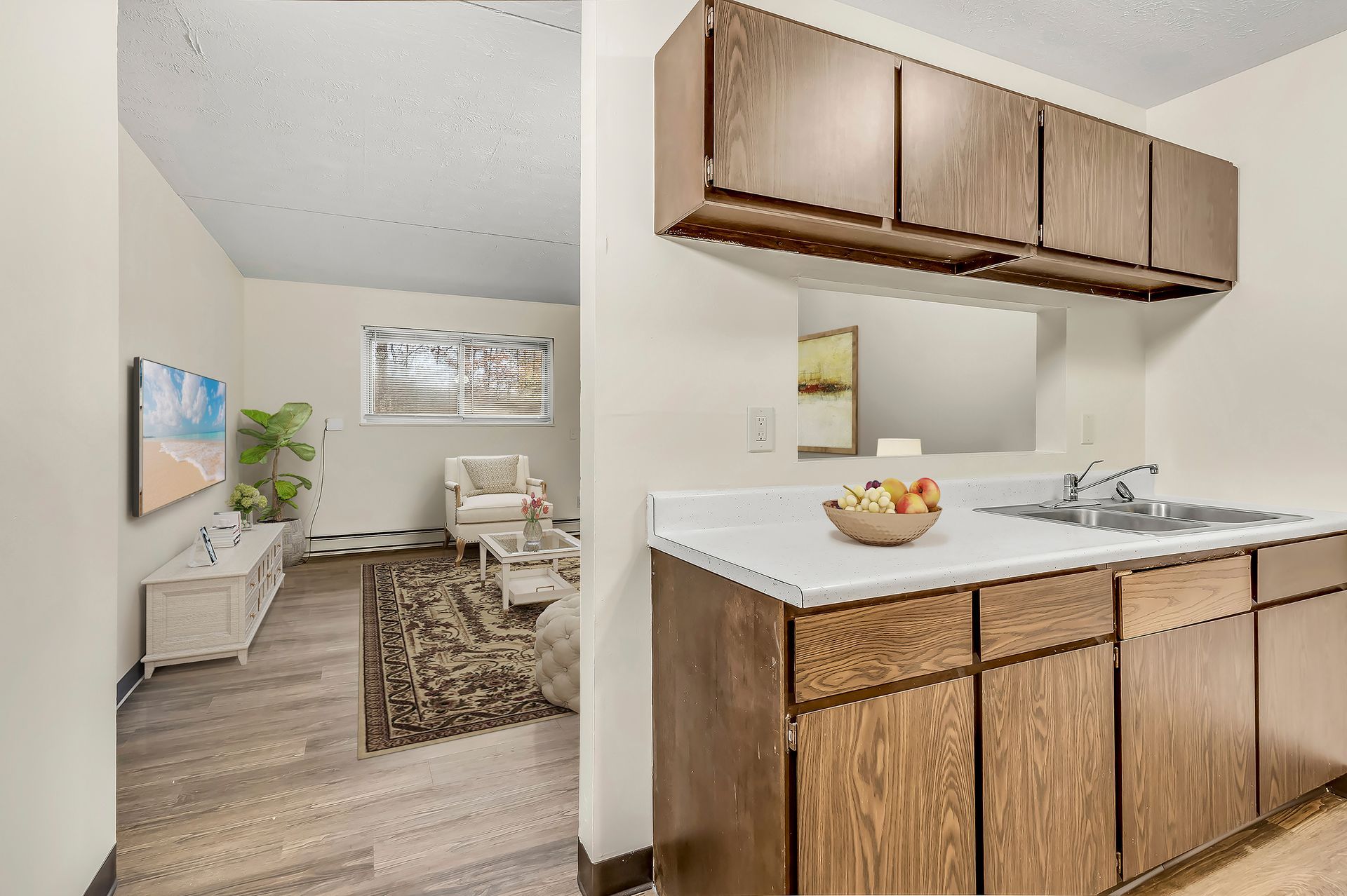 A kitchen with wooden cabinets , a sink and a mirror.