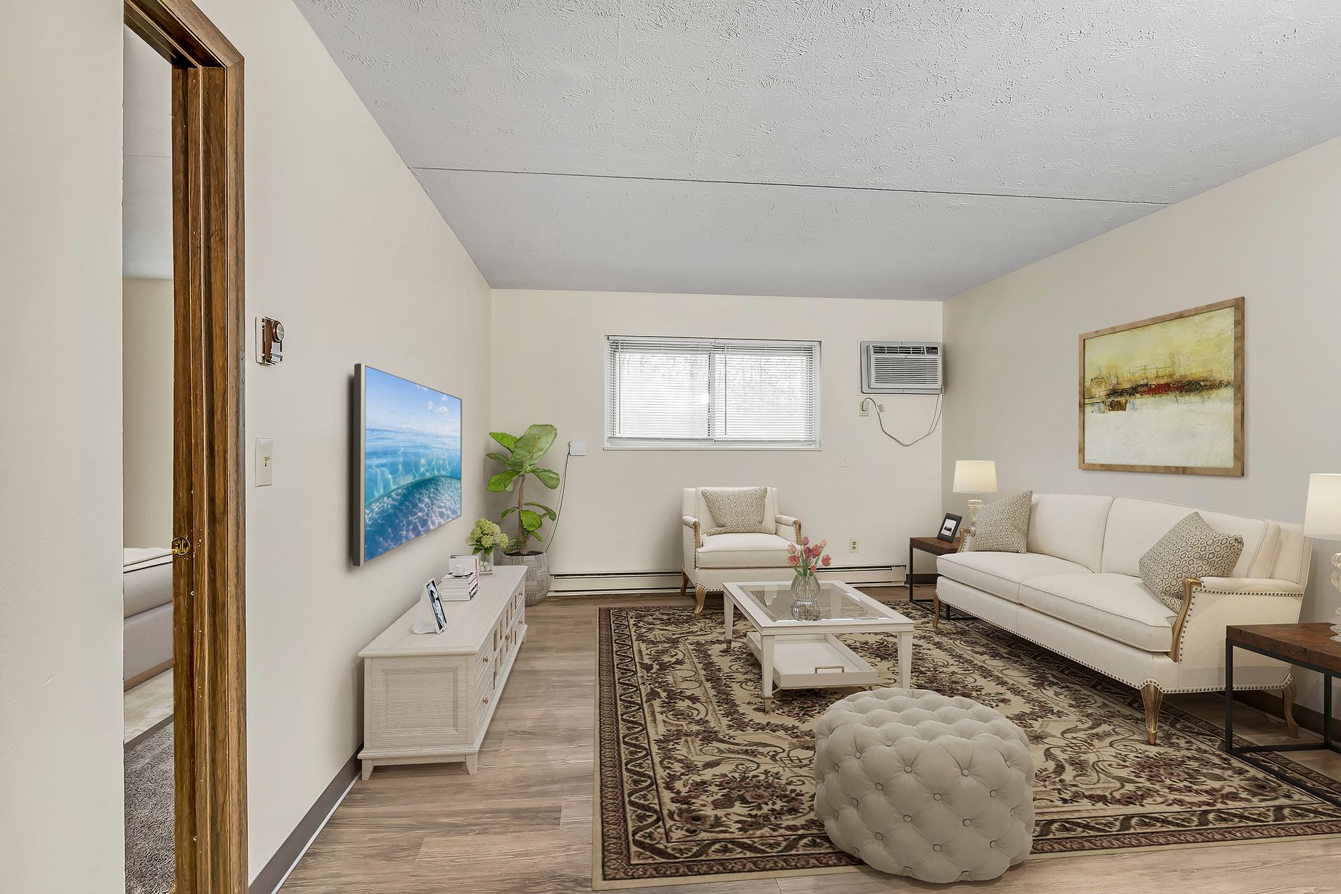 A living room with a couch , chair , coffee table and television.