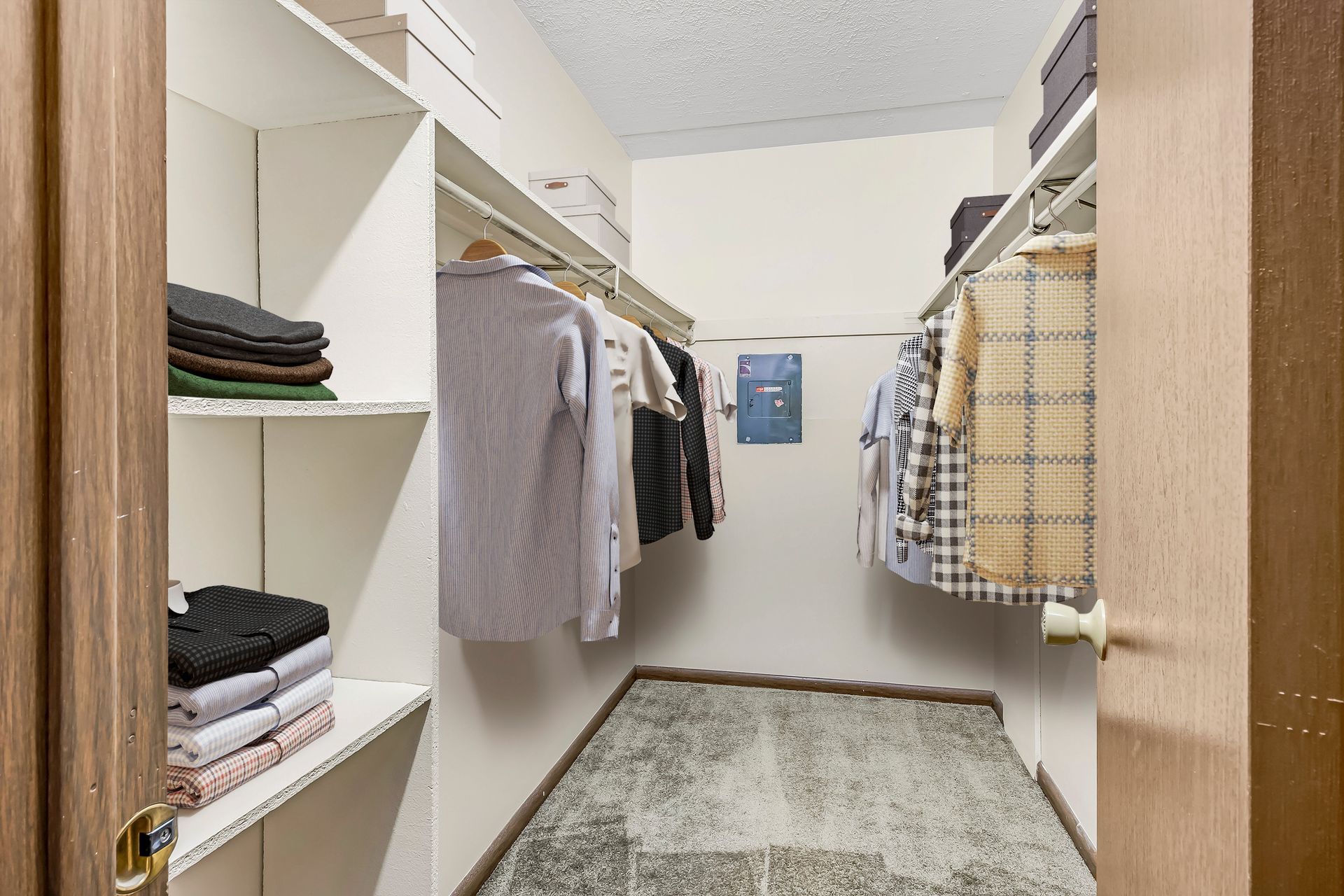 A walk in closet filled with clothes and a rug.