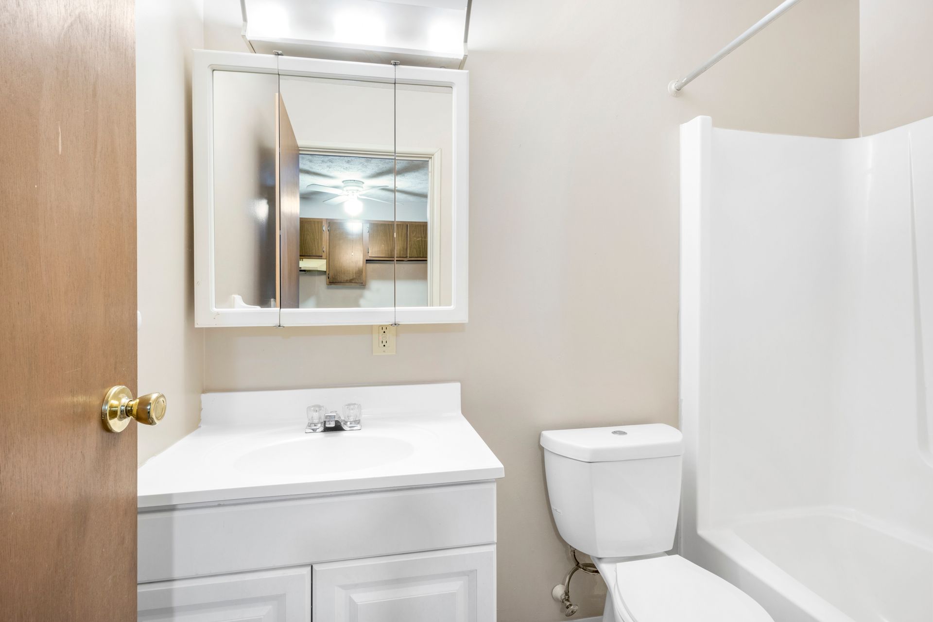 A bathroom with a toilet , sink , mirror and bathtub.