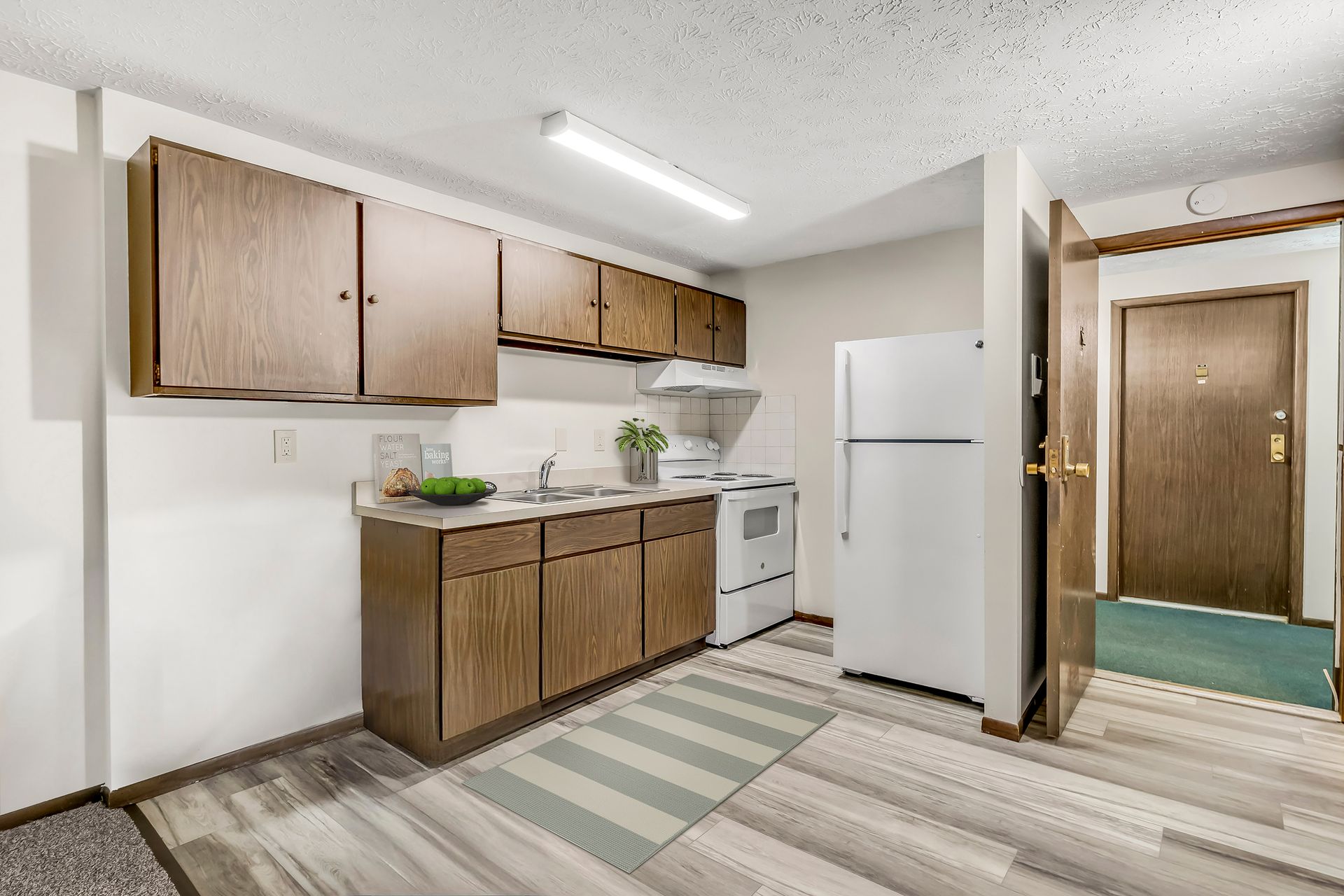 A kitchen with a refrigerator , stove , sink and cabinets.