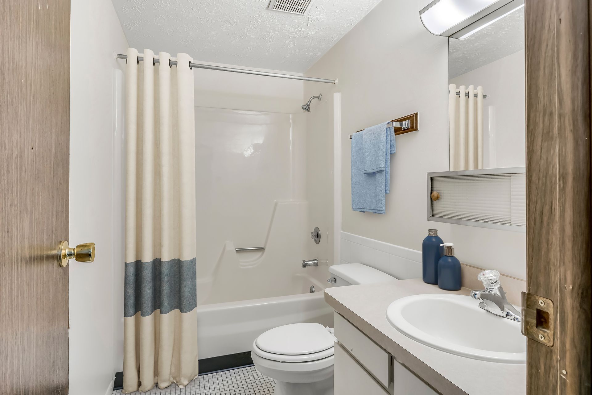A bathroom with a toilet , sink , bathtub and shower curtain.