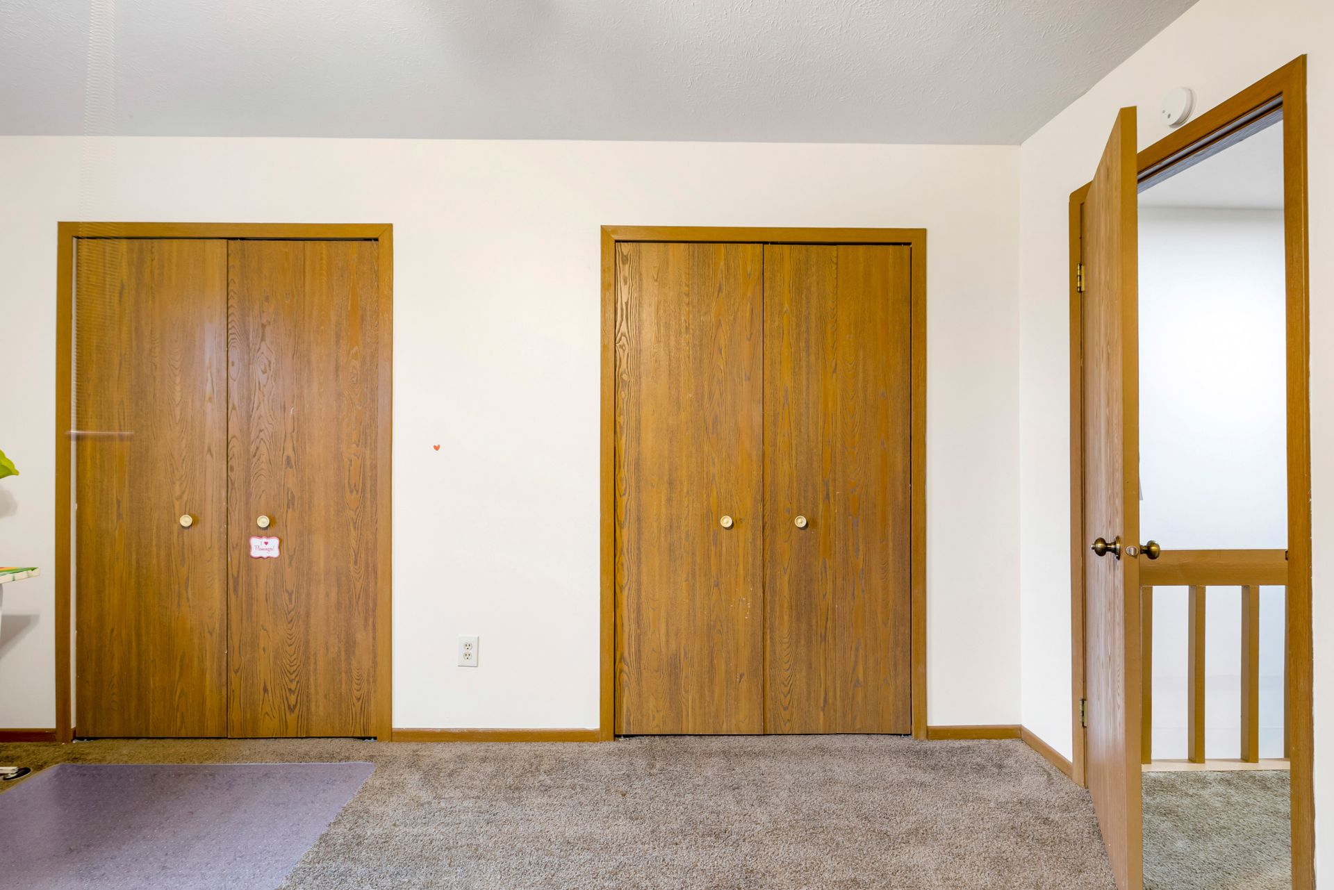 An empty room with wooden doors and a carpeted floor