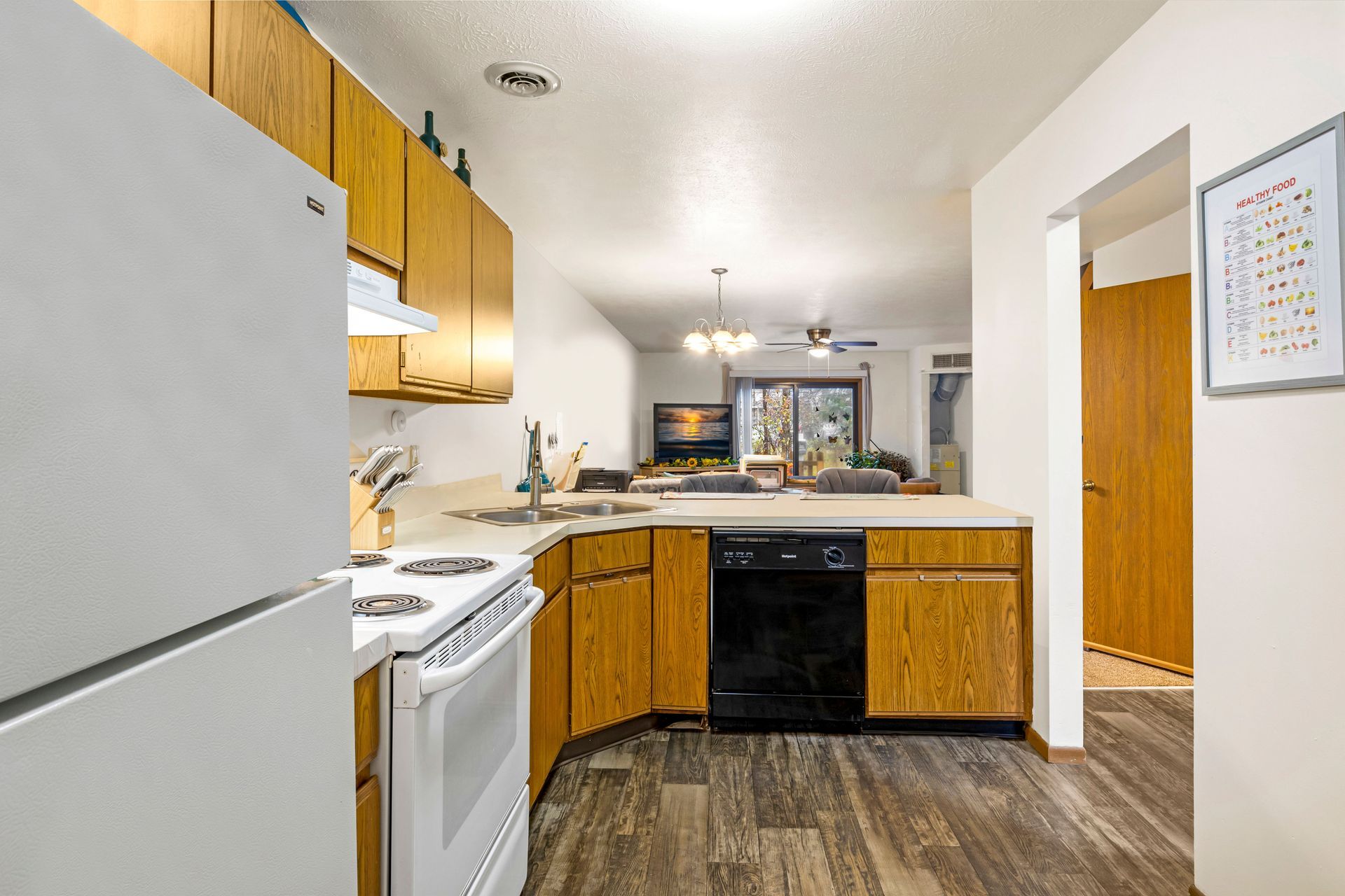 A kitchen with a refrigerator , stove , dishwasher , sink and wooden cabinets.