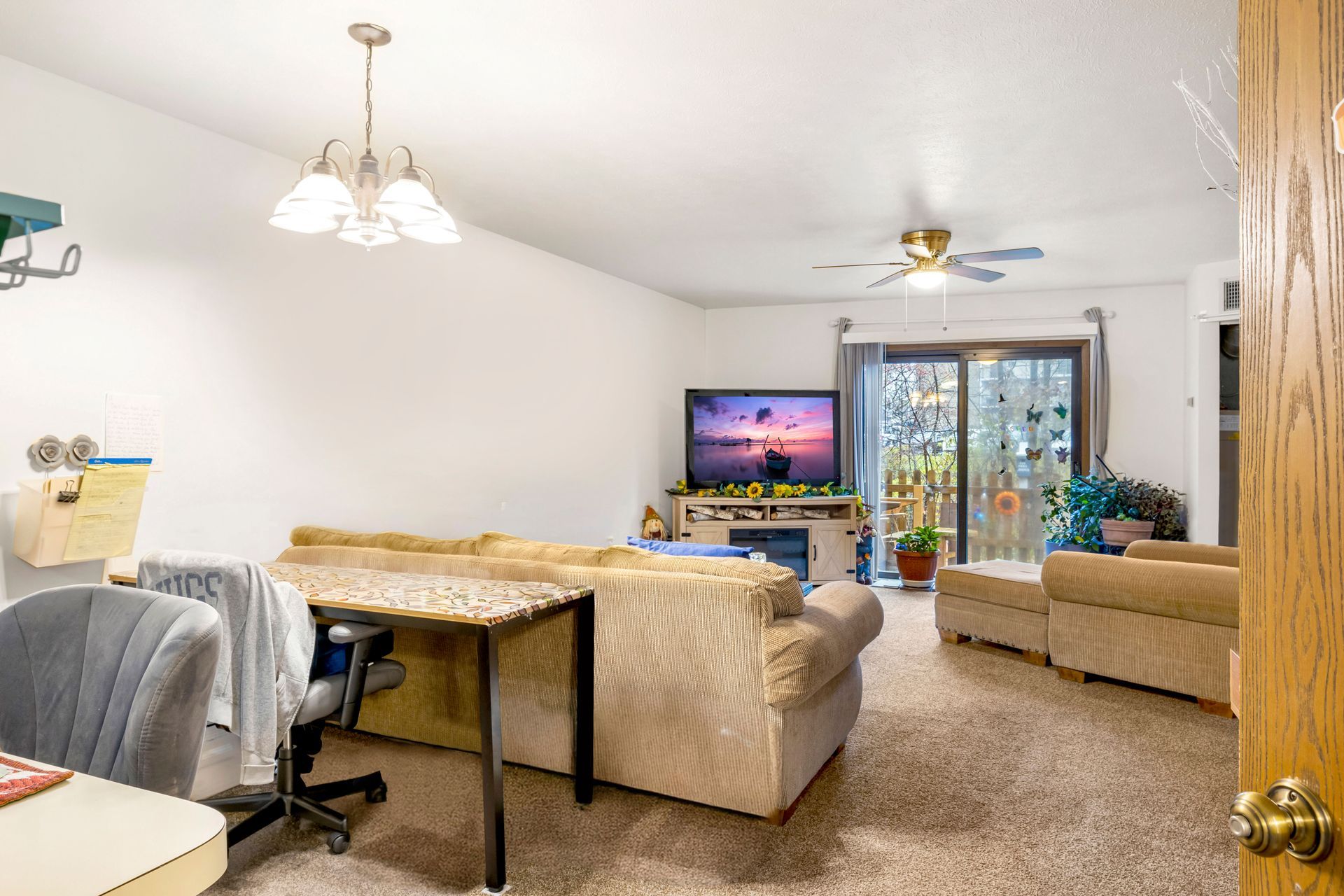 A living room with a couch , desk , chair and television.