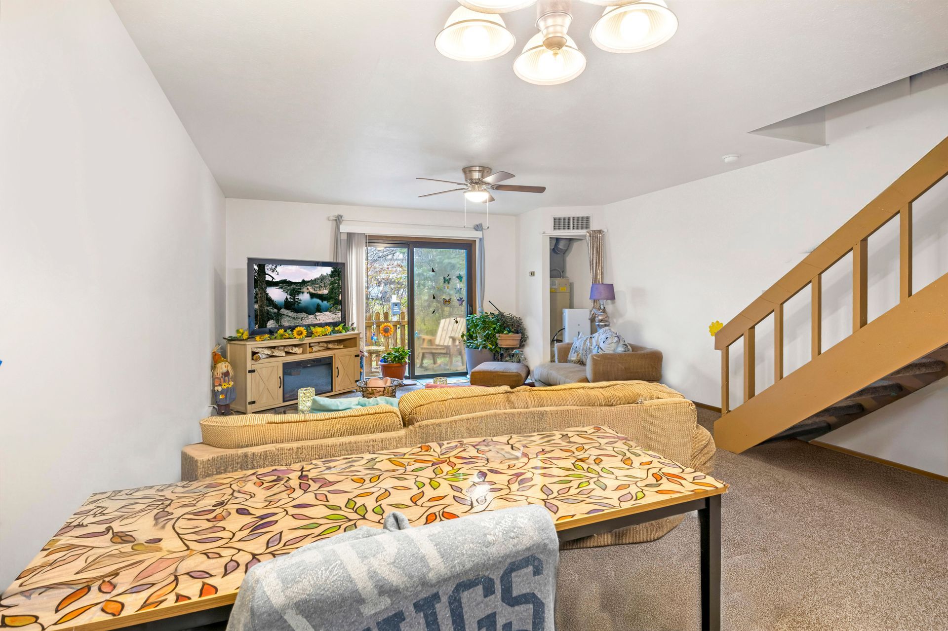 A living room with a table , couch , television and stairs.