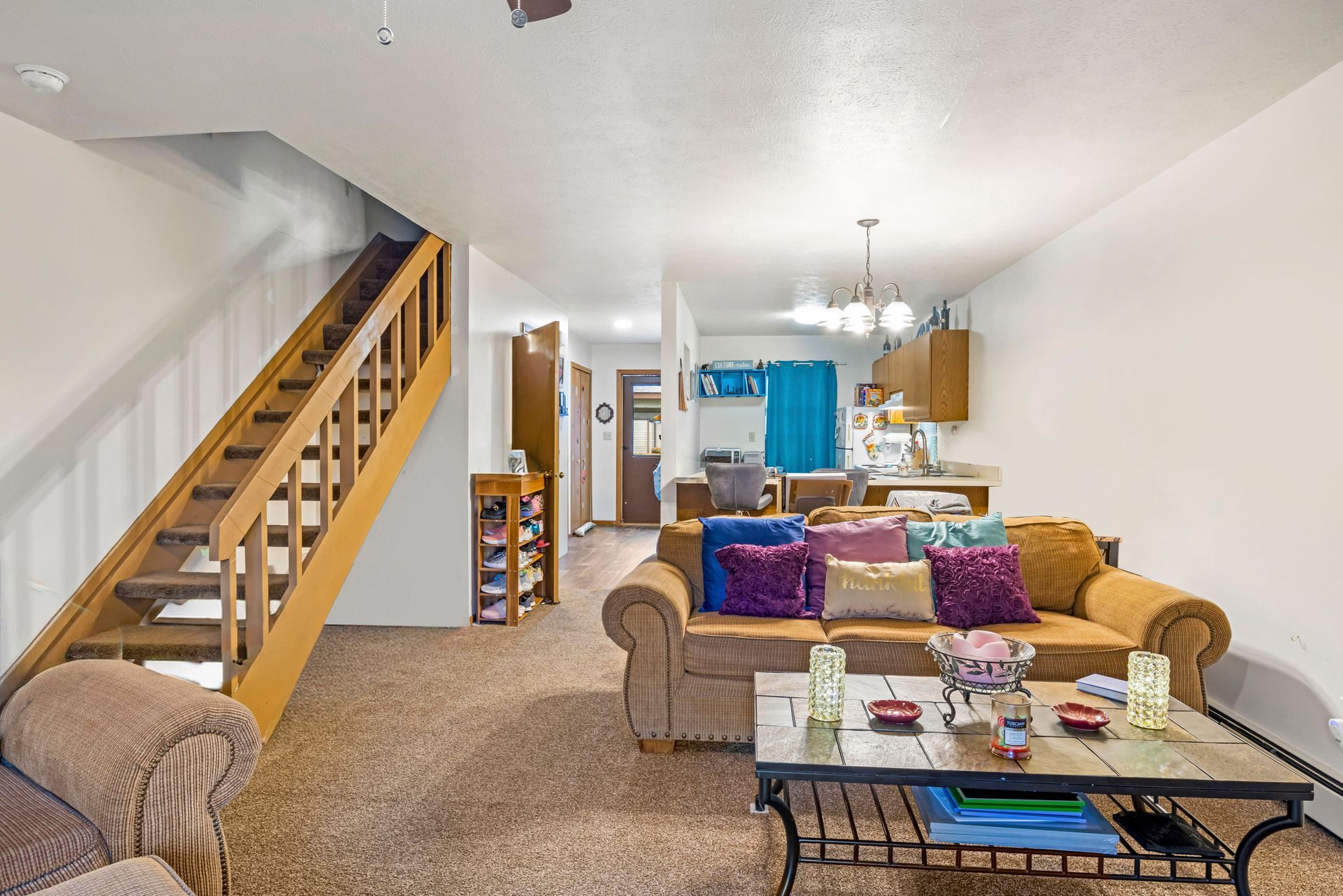 A living room with a couch , coffee table , and stairs leading up to the second floor.