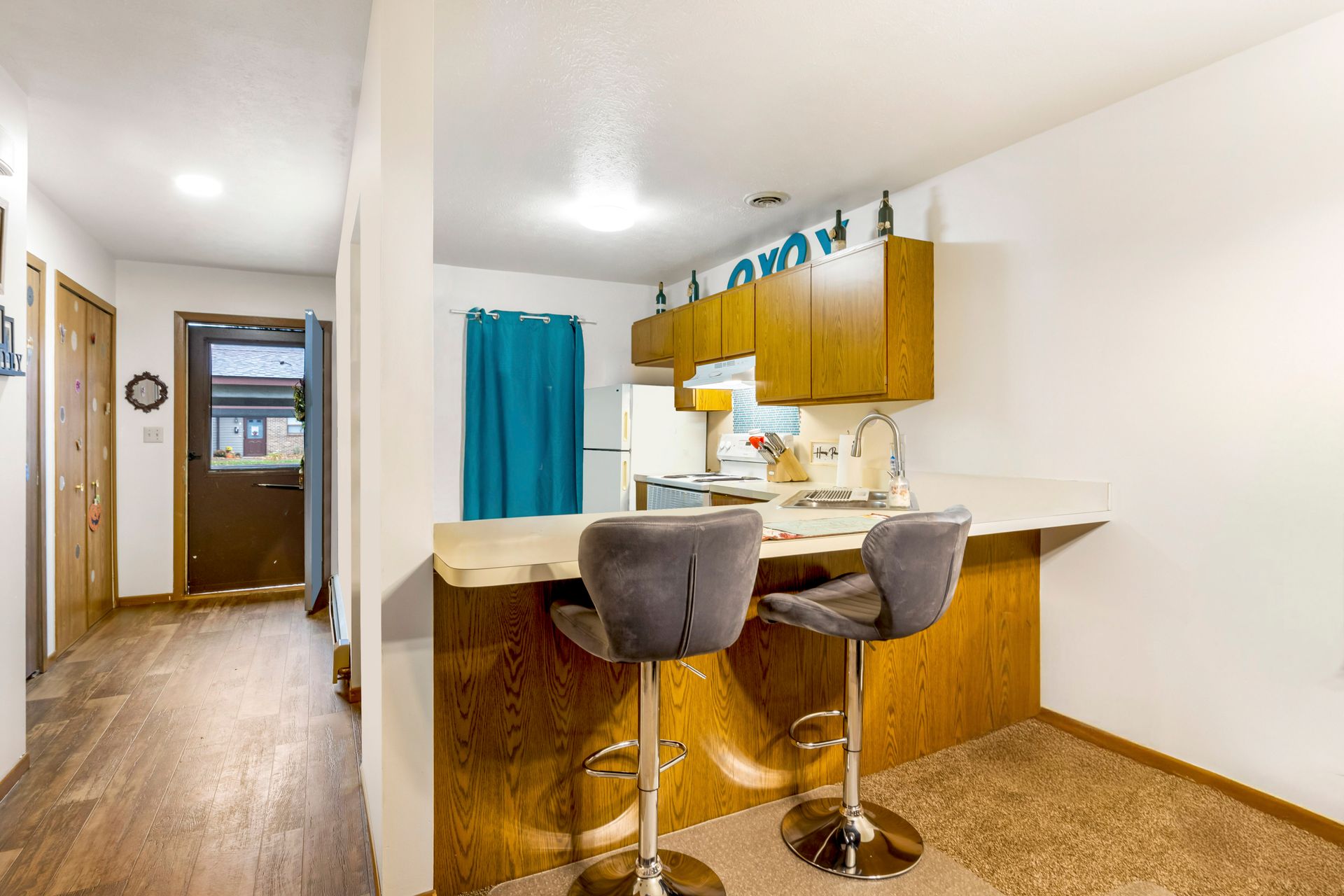 A kitchen with a bar and two bar stools.