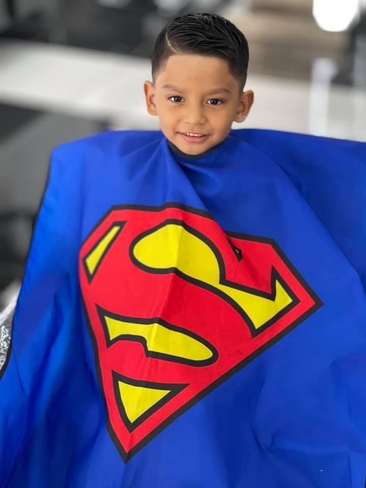 A young boy is wearing a blue cape with a superman logo on it.