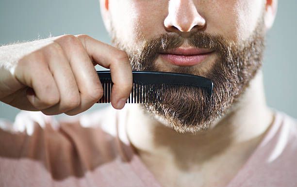 A man is combing his beard with a comb.