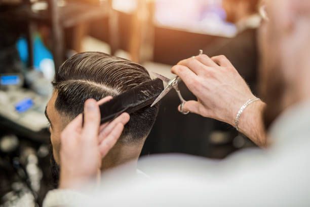 A man is getting his hair cut by a barber in a barber shop.