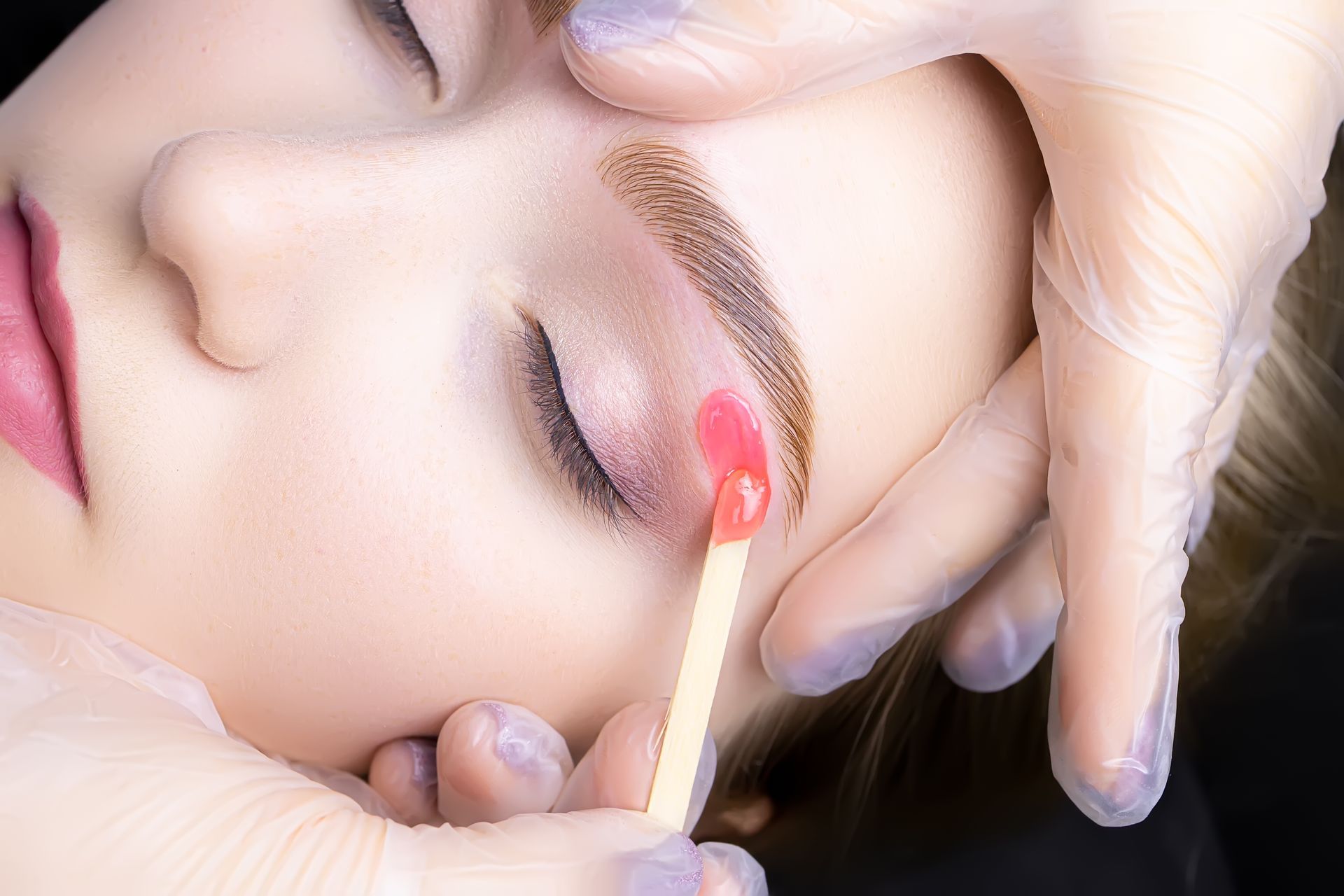 A woman is getting her eyebrows waxed with a match.