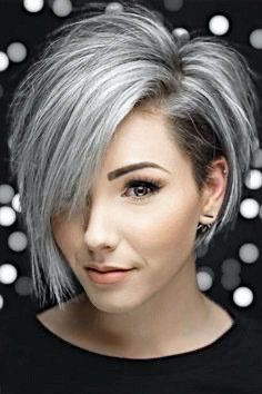 A woman with short gray hair is wearing a black shirt and earrings.