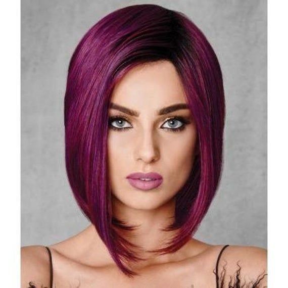 A woman with purple hair and blue eyes is wearing a purple wig.