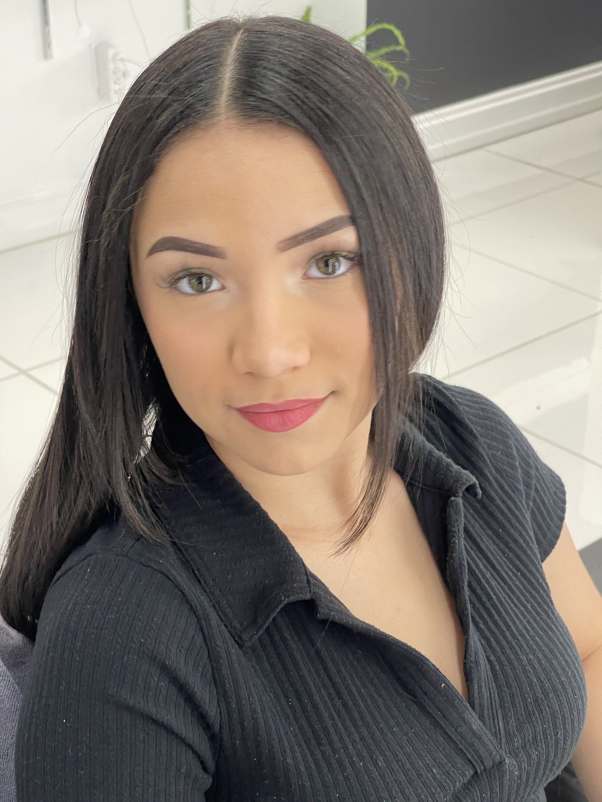 A woman in a black shirt is taking a selfie.