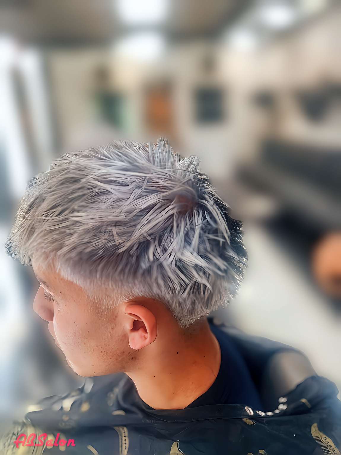 A man with gray hair is getting his hair dyed in a salon.