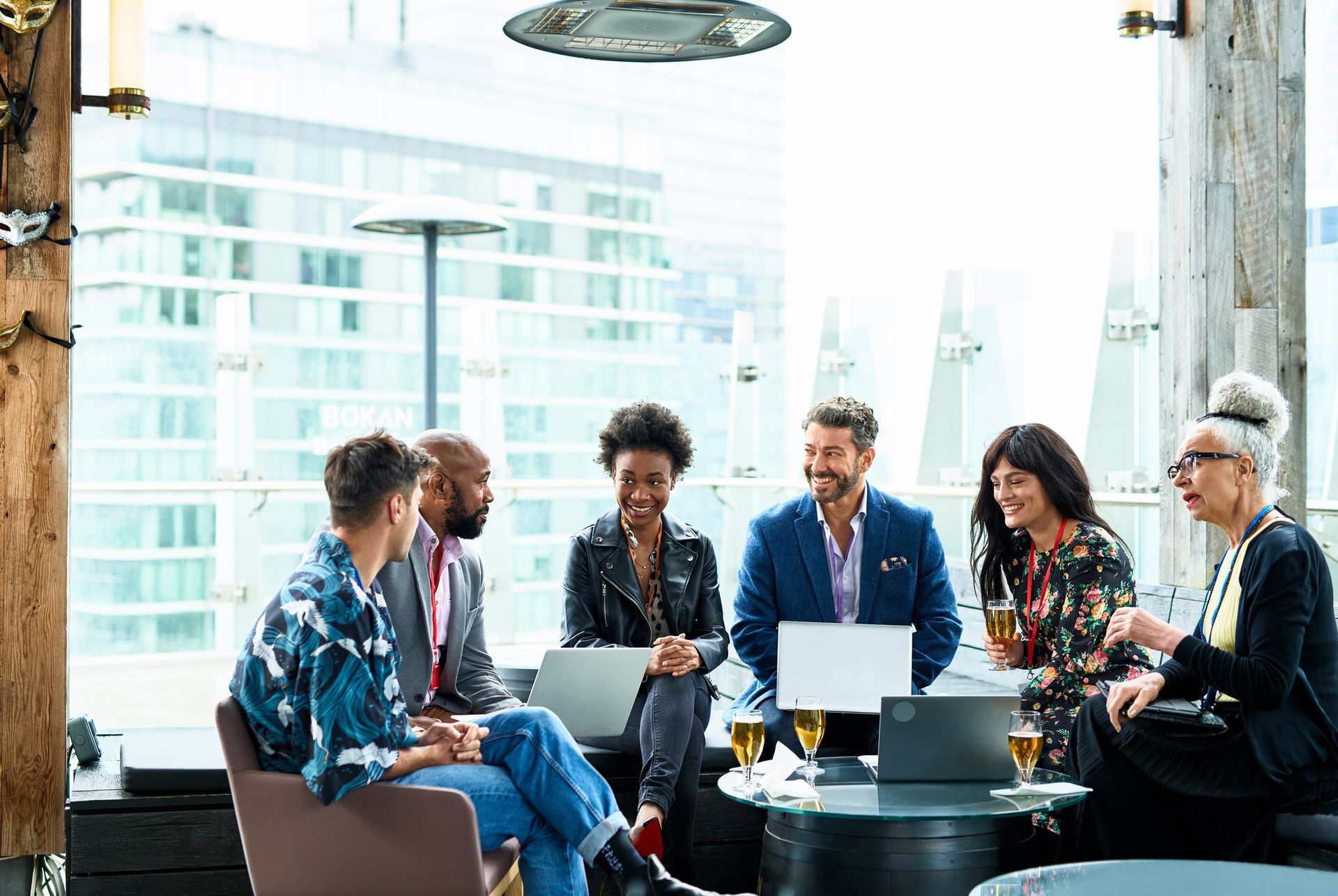 A group of people are sitting around a table with laptops.